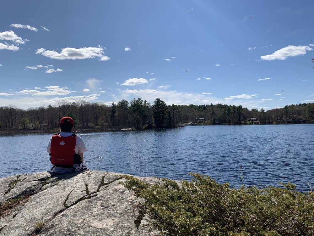 Michael sitting on a rock looking out over a lake in a life jacket